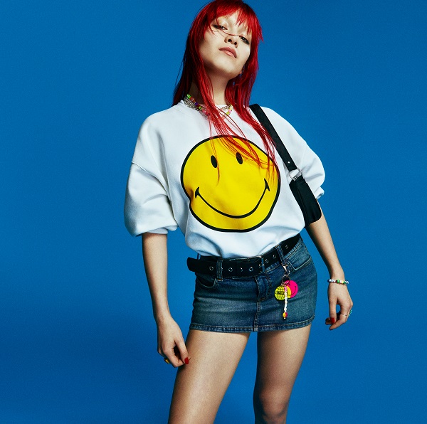 a model wearing a white jumper with a massive yellow smiley face on it