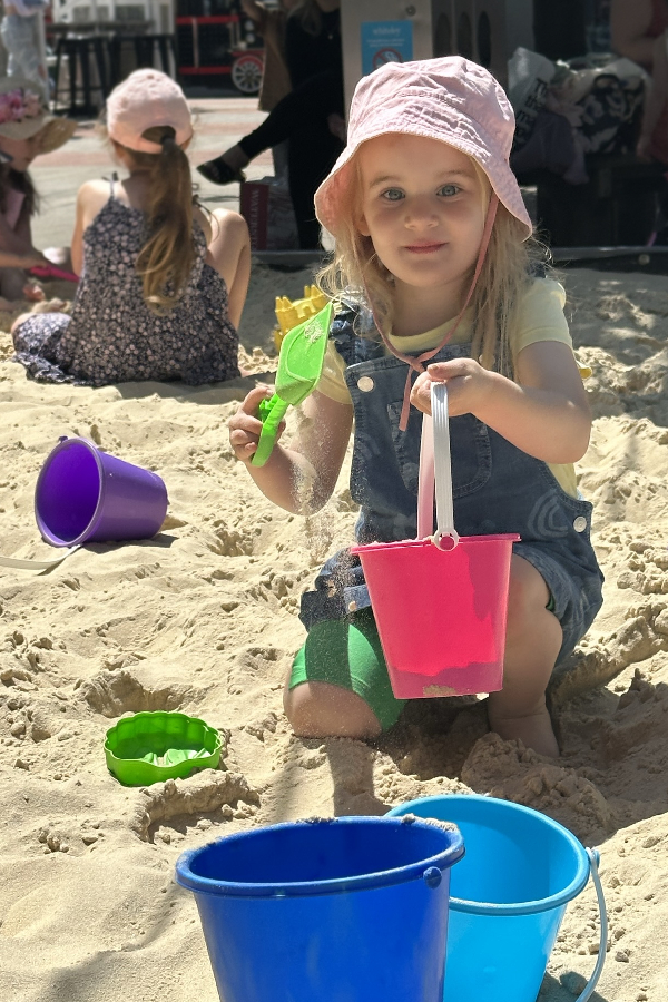 A young girl playing with bucket and spade in the sandpit.