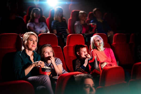 Family watching film in movie theatre and eating popcorn