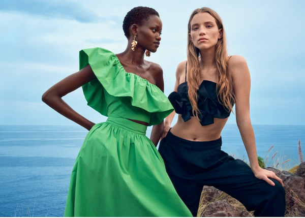 Two H&M models posing with a sea back drop