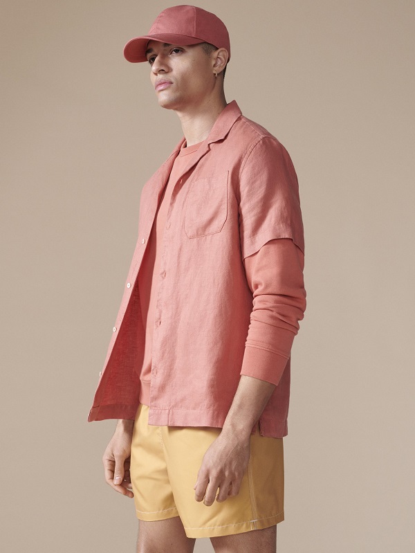 A model wearing all peach clothing including shirt shorts and cap