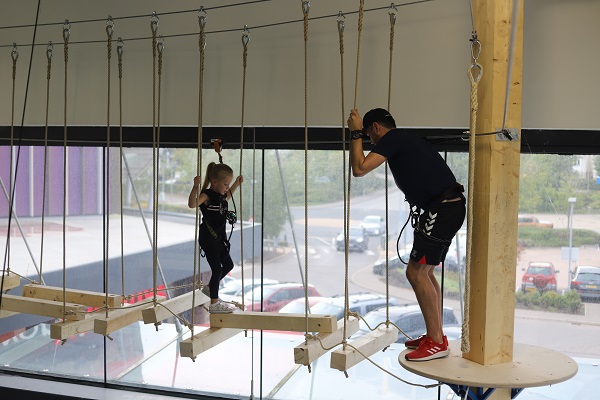A Rock Up instructor encouraging a child to walk across a suspended beam